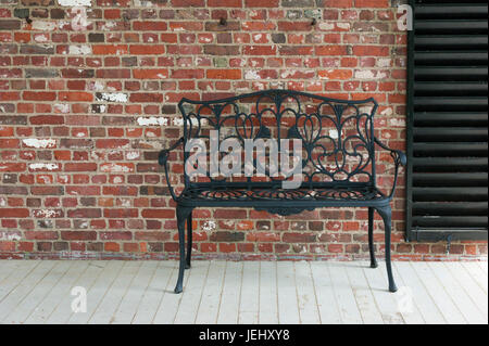 Cast iron bench against a brick wall, on the porch of the Long Hill summer residence, in Beverly, MA. Stock Photo