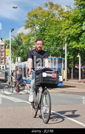 AMSTERDAM-AUGUST 27, 2014. Man with stylish beard cycling. In a city with 800,000 people, there are 880,000 bicycles. Stock Photo