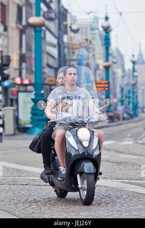 AMSTERDAM-AUG. 19, 2012. Young couple on a MIO 50 scooter at Dam Square. This popular retro style design scooter is manufactured in Taiwan. Stock Photo