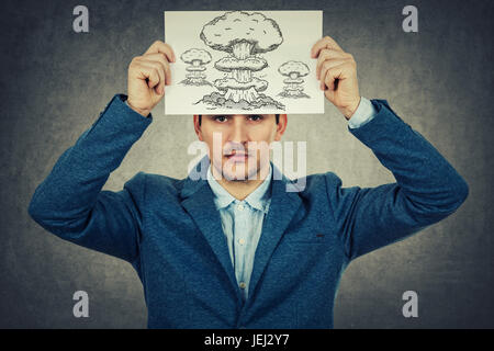 Young businessman holding a white paper over his head with a explosion drawing , isolated on grey wall background.Mental state of human depression. Stock Photo