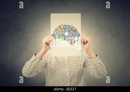 Young Student,Businesswoman covering his face with a empty white paper with a colorulful brain made from gears over her head.Creativity concept. Stock Photo