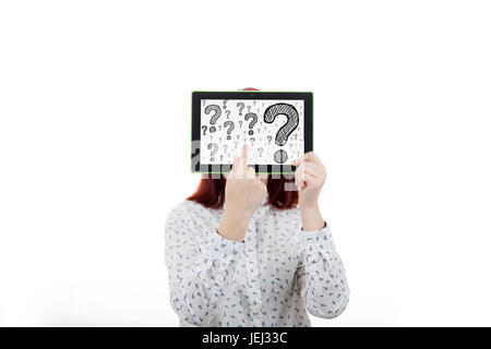 Portrait of confused, thinking young businesswoman seeks a solution, covering her face using a digital tablet with drawn question marks on the display Stock Photo
