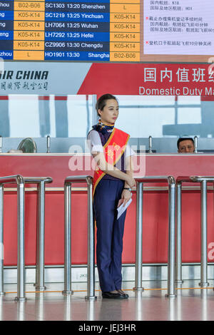BEIJING-JULY 13, 2016. Charming hostess in front of a desk at Beijing Capital International Airport, Terminal 3. Stock Photo