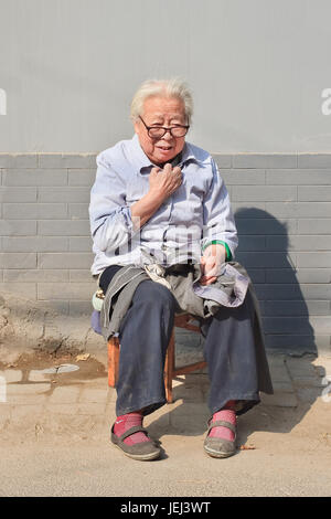 BEIJING-OCTOBER 22, 2007. Granny sit in front of her house. China’s elderly population (60 years or older) is currently about 128 million. Stock Photo