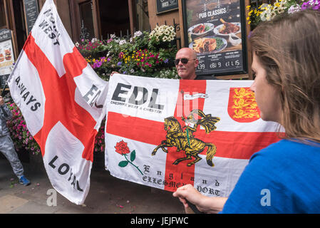 June 24, 2017 - London, UK - London, UK. 24th September 2017. A woman walks past EDL protesters at the Wetherspoons pub on Whitehall. Later police escorted a group of around 40 to Charing Cross and down a backstreet to the Embankment where they were to hold a rally. Earlier police had moved several hundred anti-fascist counter-protesters organised by UAF from their route down to a separate area of the Embankment a short distance away where they continued to protest noisily against the EDL until the police escorted them back to Charing Cross station. Both EDL and UAF had conditions for their pr Stock Photo