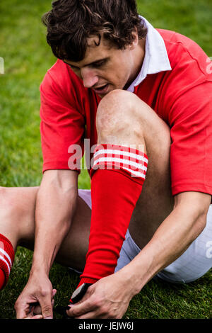 Rugby player sitting on grass Stock Photo