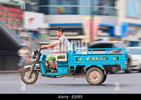 BEIJING-JULY 27, 2015. Man on electric freight tricycle in Beijing downtown. The police in major Chinese cities crackdown on unlicensed electric bikes. Stock Photo