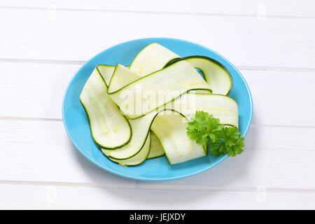 plate of raw zucchini strips on white wooden background Stock Photo