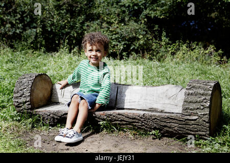 Boy on log bench Stock Photo