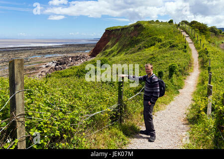 Man walking along the South West Coast Path at Helwell Bay, Watchet, Somerset Stock Photo