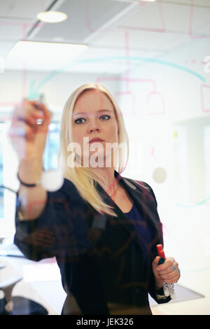 Businesswoman writing on glass board Stock Photo