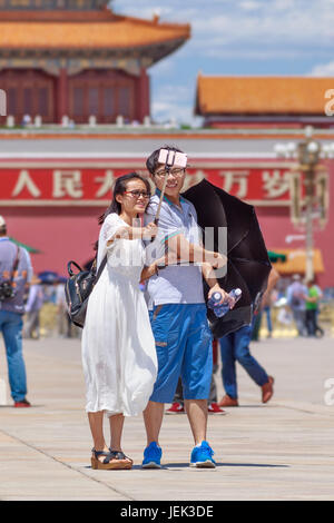 Couple takes a selfie on sunny Tiananmen Square, one of the world’s largest squares (440,500 m2). It has great cultural significance. Stock Photo