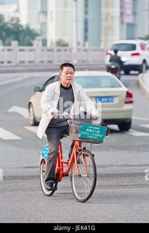 WENZHOU-NOV. 17, 2014. Man on rental bike. China has currently over 50 public bike sharing projects, dwarfing all other nations. Stock Photo