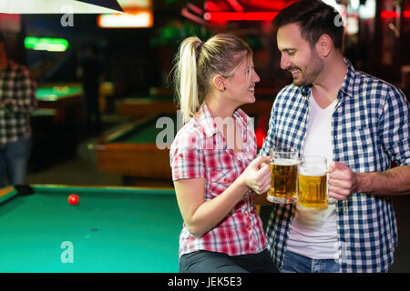 Happy couple drinking beer and playing snooker on date Stock Photo