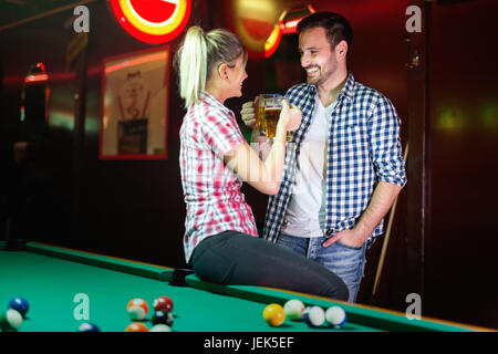 Happy couple drinking beer and playing snooker on date Stock Photo