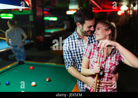Young couple playing pool in bar while having night out in town Stock Photo