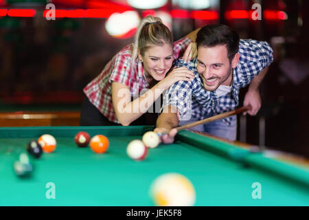 Young couple playing pool in bar while having night out in town Stock Photo