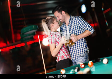 Young couple playing pool in bar while having night out in town Stock Photo