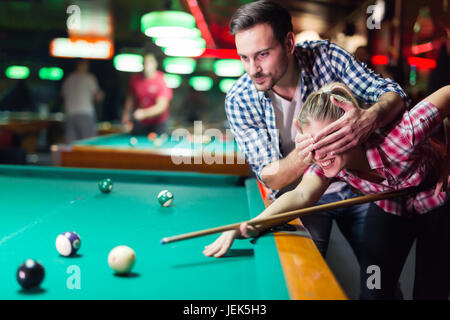 Young couple playing pool in bar while having night out in town Stock Photo