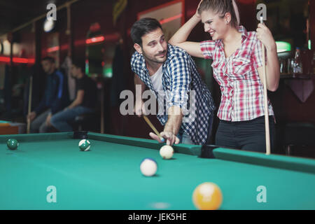 Young couple playing pool in bar while having night out in town Stock Photo