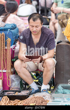 BEIJING-MAY 29, 2016. Vendor at Panjiayuan market. the largest market selling antiques, crafts, collectibles and decorations in China. Stock Photo