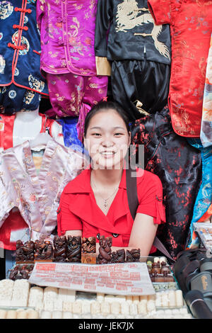 BEIJING-JULY 6. Girl in a stall with vendible on Panjiayuan Market. This market (48,500 sq. meter) is the biggest antique market in Asia. Stock Photo