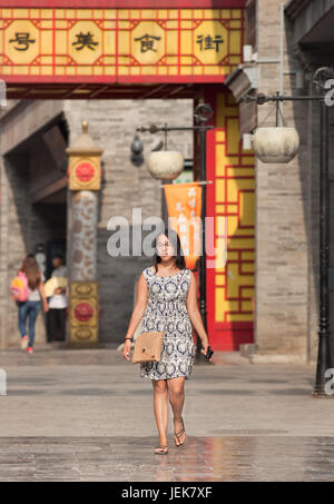 BEIJING-JUNE 9, 2015. Fashionable woman walks in Qian Men Street. Over 27 years and unmarried females in China are labelled as leftover women. Stock Photo