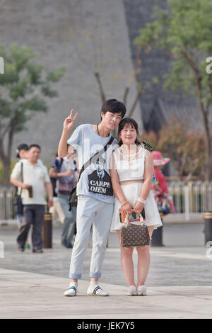 BEIJING-JUNE 9, 2015. Young couple pose for a photo on a summer day in Beijing city center with ancient watchtower on the background. Stock Photo