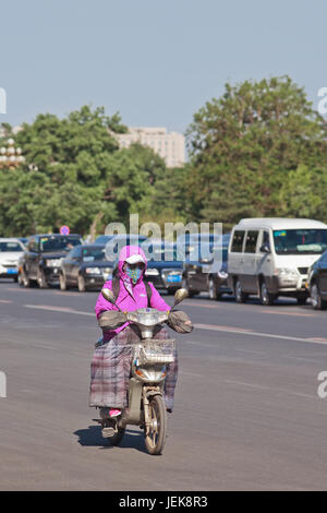 BEIJING-MAY 29, 2013. Chinese woman with breath protection on an electric bike. Stock Photo