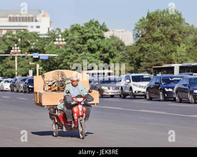 BEIJING-MAY 29, 2013. Chinese elderly transports a cabinet and folding bicycle on his electric bike. Stock Photo