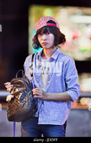 KUNMING-JULY 10, 2014. Fashionable young girl with a trendy bag in a downtown shopping area. Stock Photo