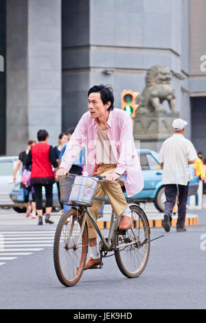 KUNMING-JUNE 30, 2014. Middle aged man cycles in city center. China has a population of 1,342,700,000, 500,000,000 bicycles and 37.2 cyclists. Stock Photo