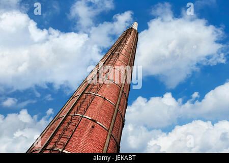 Tall brick chimney against a blue cloudy sky Stock Photo