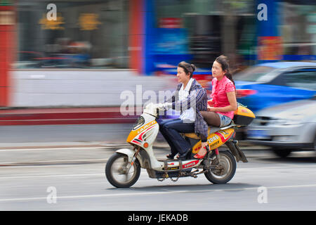 SHANGHAI–MAY 28. Two girls riding on an e-bike. Two- and three-wheeler e-bikes account for more than half of all lead consumption in China. Stock Photo