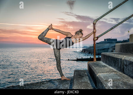 woman doing yoga at sunset by the sea Stock Photo
