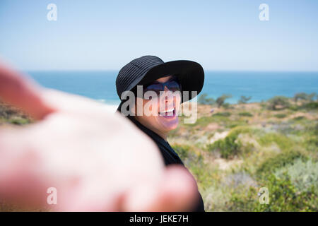 Woman on the beach with her arm outstretched to follow her Stock Photo