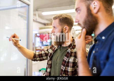 men writing to whiteboard at office Stock Photo