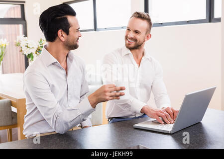 Smiling gay couple using laptop Stock Photo