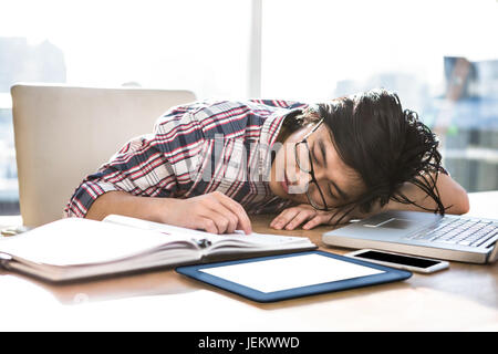 Hipster businessman falling asleep on desk Stock Photo