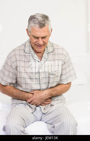 Suffering senior man holding his belly Stock Photo