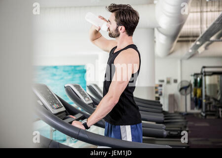 Handsome man drinking water on treadmill Stock Photo