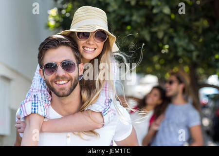 Hip man giving piggy back to his girlfriend Stock Photo