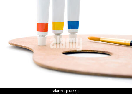 Three tubes of paint (primary colours) standing on edge of wooden palette with thumb hole and paintbrush tip visible.  Closeup shot, cropped in camera Stock Photo