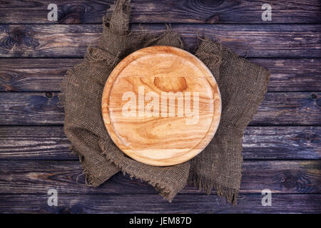 Round tray for pizza on dark wooden table. Cutting board on rustic background. Top view. Copy space. Stock Photo