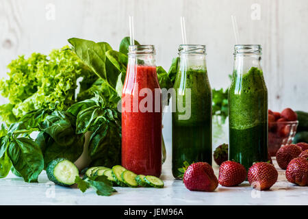 Fresh green smoothies and strawberry smoothie with ingredients on a light wooden background. Healthy detox drinks. Stock Photo