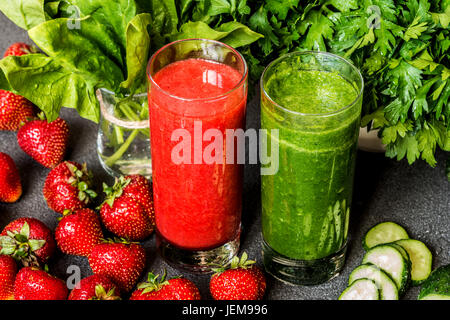 Strawberry smoothie and green smoothie in two glasses with ingredients on a gray background. Detox healthy drinks. Stock Photo
