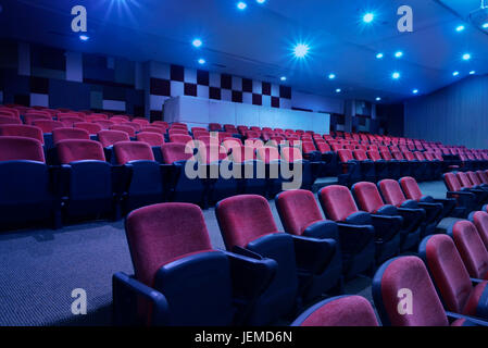 Bright blue light with black armchairs in movie theater Stock Photo