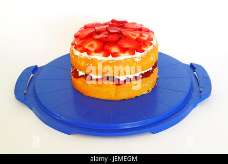 A homemade Victoria sponge on a blue cake stand against a white background. Stock Photo