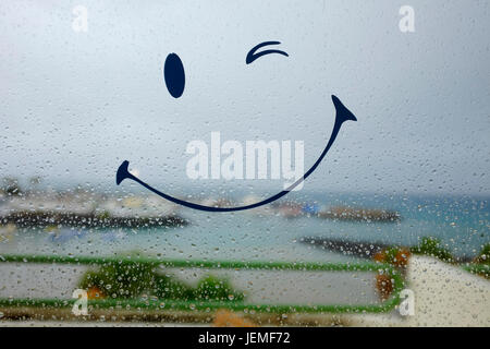 Smiley face on rainy window Stock Photo