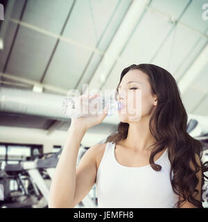Composite image of brunette drinking water Stock Photo